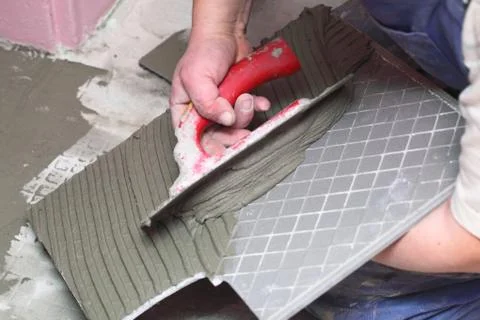 Construction worker is tiling at home tile floor adhesive 库存照片