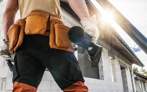 Construction Worker With Tool Belt and Gutter Element in His Hand Foto stock