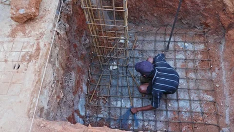 Construction worker Tying binding wire to column using Binding Hook in footing Stock Footage 327844769