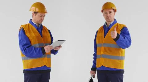 Construction worker in uniform and hardhat using tablet PC and showing thumb up Stock Photos