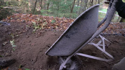 Construction worker unloads wheelbarrow full of soil Stock Footage 158979470