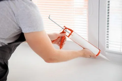 Construction worker use gun silicone tube for repairing and installing window in Stock Photos