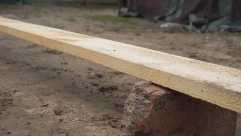 Construction worker uses a chainsaw to cut a long wooden plank. Stock Footage 129778495