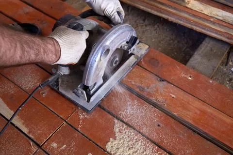 A construction worker uses a circular saw to cut wooden planks in a workshop Photos
