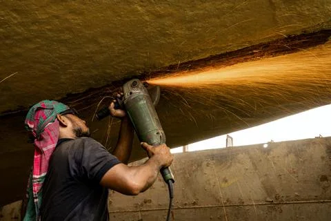 Construction Worker Uses Grinder to Cut Metal, Sparks Flying Foto stock