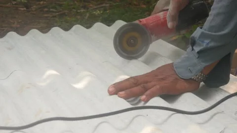A construction worker uses a hand grinder to cut asbestos Stock Footage 333346835
