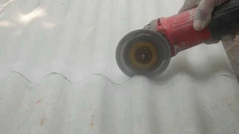 A construction worker uses a hand grinder to cut asbestos Stock Footage 333346860