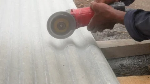 A construction worker uses a hand grinder to cut asbestos Stock Footage 333346868