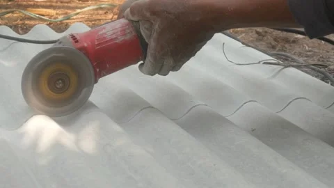 A construction worker uses a hand grinder to cut asbestos Stock Footage 333346918