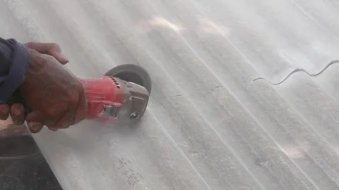 A construction worker uses a hand grinder to cut asbestos Stock Footage 333346939