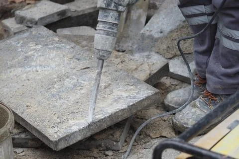 Construction worker uses jackhammer on pavement in a city Stock Photos