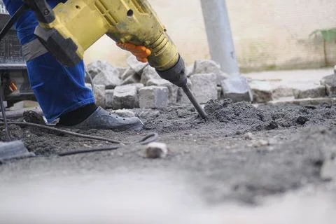 Construction worker uses a jackhammer on a pavement renovation project Stock Photos