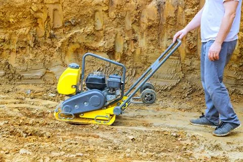 Construction worker uses plate compactor for soil compaction on constructio.. Stock Photos
