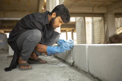 A construction worker uses a plumb bob measuring tool to accurate a brick wall. Stock Photos