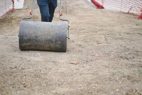 Construction worker uses roller on gravel path Photos