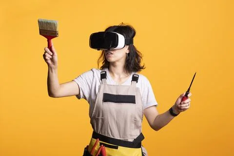 Construction worker uses screwdriver and paintbrush in virtual simulation Stock Photos