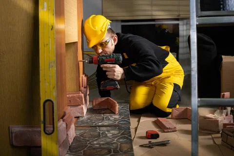 A construction worker uses a screwdriver to screw the screws into the furniture Stock-Fotos