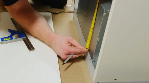 Construction worker uses tape measure to check height of cabinet Video stock 304401973