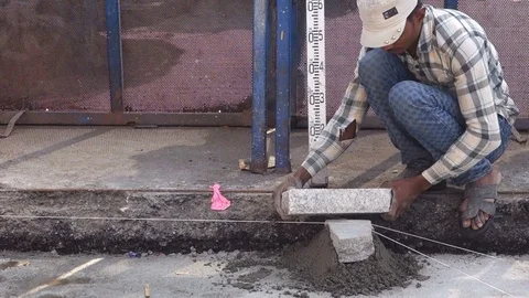 Construction worker uses thread and stone to level the pavement Stock Footage 83635322