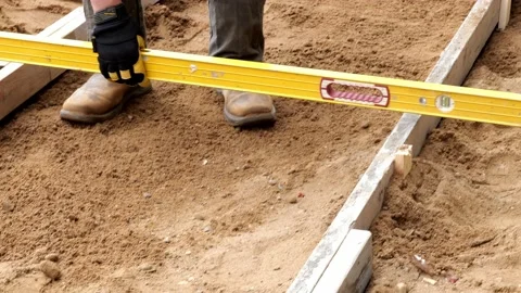 Construction worker uses a yellow level to check form for concrete sidewalk. Stock Footage 154433953