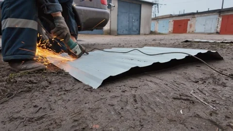 Construction worker using angle grinder cutting corrugated metal sheet 库存影片 333697311