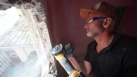 Construction worker using an angle grinder to cut a wall 库存影片 347640512