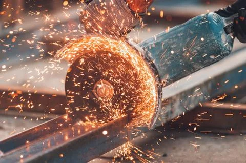 Construction worker using Angle Grinder cutting Metal at construction site. Stock Photos
