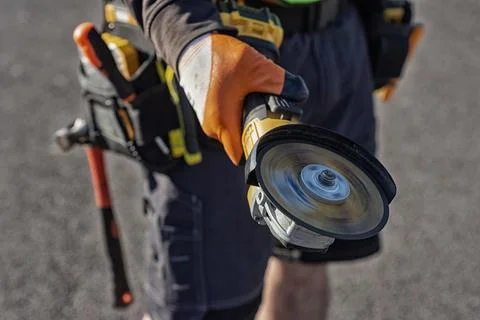 Construction worker using angle grinder power tool with rotating cutting di.. Foto stock