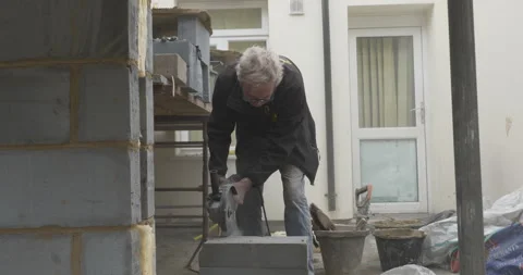 Construction worker using circular saw to cut through breeze block close-up Stock Footage 246380617