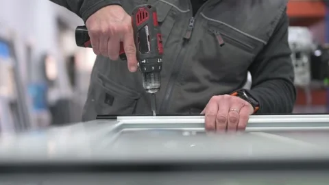 Construction worker using cordless drill on aluminum window frame Stock Footage 309338007