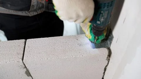 Construction worker using a cordless drill to fasten a metal bracket to a c.. Fotos Stock
