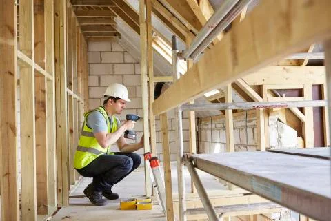 Construction worker using drill on house build Stock Photos