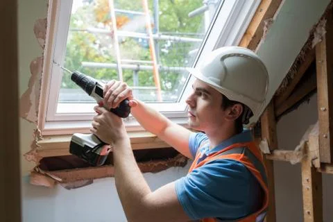 Construction Worker Using Drill To Install Replacement Window Stock Photos