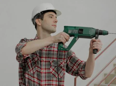 A construction worker using a drill on a wall Stock Photos