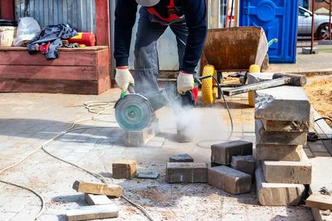 A construction worker using an electric grinder and a diamond cutting disc cu Stockfoto's