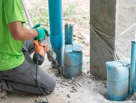 Construction worker using an electric jackhammer to break up concrete aroun.. Stock Photos