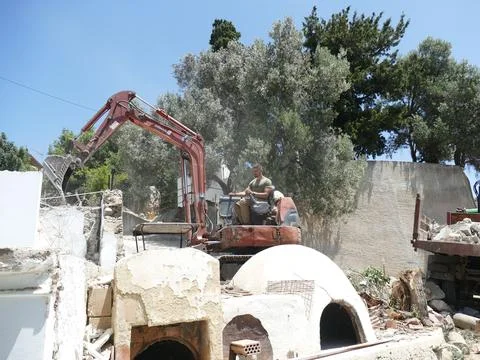 Construction worker using an excavator to demolish a wall, with rubble and .. Stock Photos