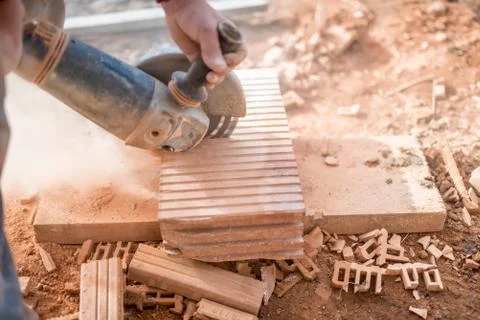 Construction worker using an grinder for cutting and sawing construction bricks Stock Photos