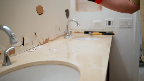 Construction worker using a hammer to break and remove bathroom countertop Stock Footage 332185790
