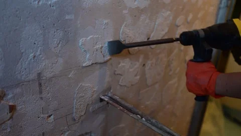 Construction worker using a hammer drill to remove plaster Stockbeeldmateriaal 346958794