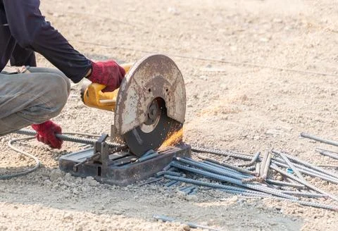 A construction worker using a heavy-duty metal chop saw to cut rebar on a d.. Stock Photos