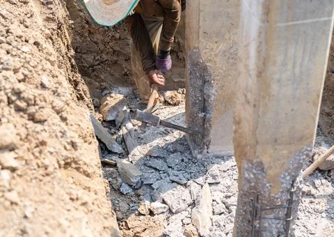 Construction worker using a heavy sledgehammer and steel chisel. Stock Photos