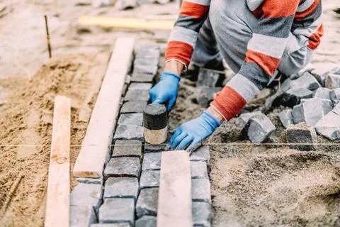 Construction worker using industrial tools for stone pavement. granite blocks Stock Photos