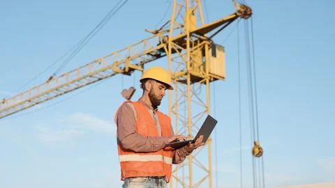 Construction worker using laptop to manage project on site with crane Video stock 311307845