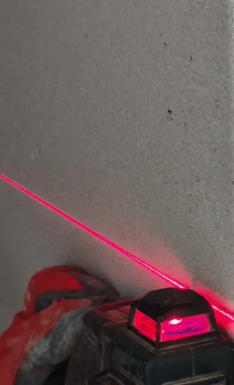 Construction Worker Using Laser Level for Wall Panel Alignment Vertical Stock Footage 332932061