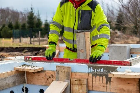 Construction Worker Using Level on Insulated Concrete Forms at Building Site Foto stock