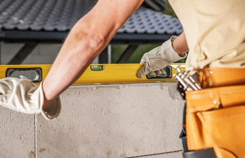 Construction Worker Using Level Tool on Block Wall at Job Site Stock Photos