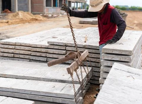 Construction worker using a lifting clamp mechanism and chain rigging to mo.. Stock Photos