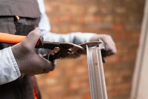 Construction worker using metal shears snips cut of galvanized steel from dry Stock Photos