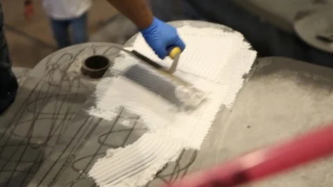 Construction worker using notched trowel to lay mortor for floor B Stock Footage 114924869